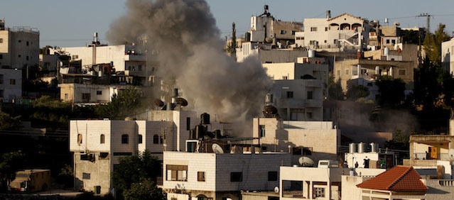 Smoke rises from the family home of Palestinian Ziad Awad in the town of Idna, 13 kilometers (8 miles) west of the West Bank city of Hebron, Wednesday, July 2, 2014. Israel demolished on Wednesday the West Bank home of Ziad Awad, who it accuses of having killed an Israeli police officer in April. The move marks a return to a policy abandoned by the military in 2005. Israel sees house demolitions as a deterrent to violence while critics charge it is a form of collective punishment. (AP Photo/Nasser Shiyoukhi)