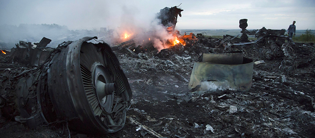 A man walks amongst the debris at the crash site of a passenger plane near the village of Grabovo, Ukraine, Thursday, July 17, 2014. Ukraine said a passenger plane carrying 295 people was shot down Thursday as it flew over the country, and both the government and the pro-Russia separatists fighting in the region denied any responsibility for downing the plane. (AP Photo/Dmitry Lovetsky)