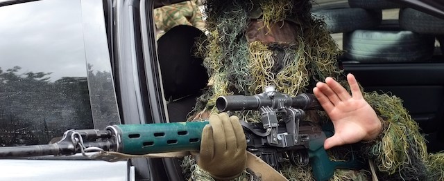 A Pro-Russian sniper gestures as he sits in a car while guarding the front entrance of Lugansk's regional administration building on July 9, 2014. Ukrainian President Petro Poroshenko looked set to face renewed European pressure today for a truce with pro-Russian rebels as the remaining separatist strongholds braced for more fighting. In Lugansk -- one of two regional capitals still held by the insurgents -- the streets were deserted and an AFP team heard regular artillery fire to the north of the city with shooting seeming to be focused around the rebels' military headquarters. Three people were killed in the city and five injured over the past 24 hours, local authorities said. AFP PHOTO / DOMINIQUE FAGET (Photo credit should read DOMINIQUE FAGET/AFP/Getty Images)