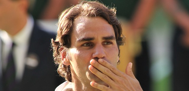 Runner up Switzerland's Roger Federer blows a kiss to spectators as he is presented with his trophy after losing the men's singles final match to Serbia's Novak Djokovic on day thirteen of the 2014 Wimbledon Championships at The All England Tennis Club in Wimbledon, southwest London, on July 6, 2014. Djokovic won his second Wimbledon title and seventh career major with a 6-7 (7/9), 6-4, 7-6 (7/4), 5-7, 6-4 victory over Roger Federer Sunday, shattering the Swiss star's dream of a record eighth triumph in a titanic struggle. AFP PHOTO / GLYN KIRK - RESTRICTED TO EDITORIAL USE (Photo credit should read GLYN KIRK/AFP/Getty Images)