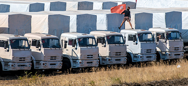 A driver installs a red flag on his lorry, parked with other lorries of the Russian humanitarian convoy not far from a checkpoint at the Ukrainian border some 30 km outside the town of Kamensk-Shakhtinsky in the Rostov region, on August 20, 2014. A tension between Moscow and Kiev simmering over Russia's decision to try and deliver what it claims to be a huge humanitarian aid convoy that the Ukrainian authorities fear may be used to smuggle in arms to the pro-Kremlin insurgents. AFP PHOTO / DMITRY SEREBRYAKOV (Photo credit should read DMITRY SEREBRYAKOV/AFP/Getty Images)