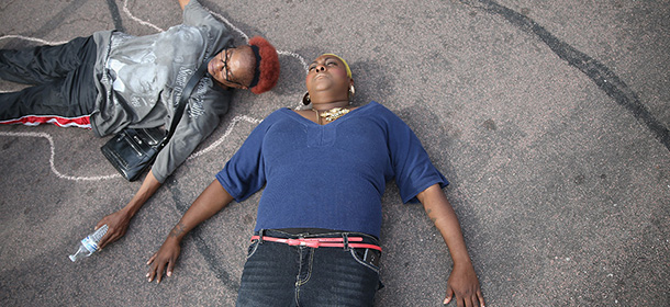 CLAYTON, MO - AUGUST 20: Protesters lay on the ground to draw lines around their bodies as they and other demonstrators protest outside of the Buzz Westfall Justice Center where a grand jury will begin looking at the circumstances surrounding the fatal police shooting of an unarmed teenager Michael Brown on August 20, 2014 in Clayton, Missouri. Brown was shot and killed by a Ferguson, Missouri police officer on August 9. Despite the Brown family's continued call for peaceful demonstrations, violent protests have erupted nearly every night in Ferguson since his death (Photo by Joe Raedle/Getty Images)