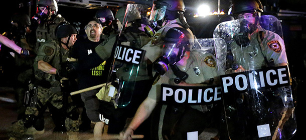 A man is detained after a standoff between protesters and police Monday, Aug. 18, 2014, during a protest for Michael Brown, who was killed by a police officer Aug. 9 in Ferguson, Mo. Brown's shooting has sparked more than a week of protests, riots and looting in the St. Louis suburb. (AP Photo/Charlie Riedel)