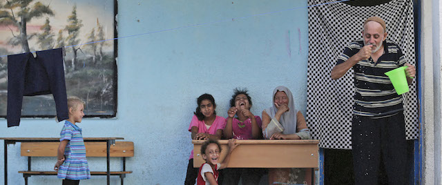 Abu Amjad Nofal, un profugo palestinese di 60 anni, si lava la faccia facendo ridere il resto della sua famiglia, in una scuola dell'ONU trasformata in centro per rifugiati a Gaza, 7 agosto 2014 
(AP Photo/Lefteris Pitarakis)