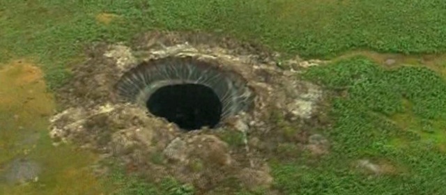 This frame grab made Wednesday, July 16, 2014, shows a crater, discovered recently in the Yamal Peninsula, in Yamalo-Nenets Autonomous Okrug, Russia. Russian scientists said Thursday July 17, 2014 that they believe the 60-meter wide crater, discovered recently in far northern Siberia, could be the result of changing temperatures in the region. Andrei Plekhanov, a senior researcher at the Scientific Research Center of the Arctic, traveled on Wednesday to the crater. Plekhanov said 80 percent of the crater appeared to be made up of ice and that there were no traces of an explosion, eliminating the possibility that a meteorite had struck the region. (AP Photo/Associated Press Television)