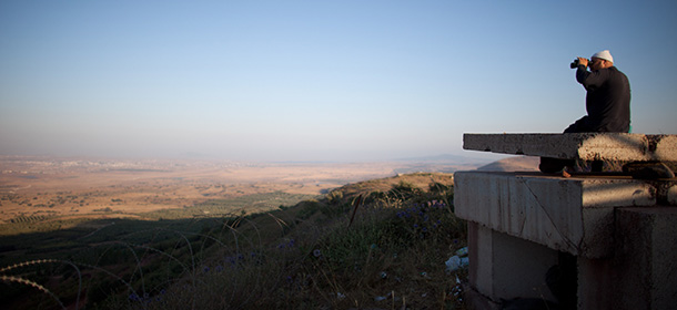 GOLAN HEIGHTS - JULY 24: A Druze man looks at the nearby Syrian village of Jebata al-Khashabn from an Israeli army post near the village of Buqaata at the Israeli side of the border on July 24, 2012 in the Golan Heights. With ongoing fighting in Syria, Israel stated it would prevent refugees from entering the Israeli-controlled Golan Heights if they try to flee there. (Photo by Uriel Sinai/Getty Images)