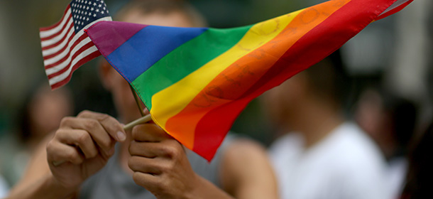 MIAMI, FL - JULY 02: A protester holds an American flag and rainbow flag in front of the Miami-Dade Courthouse to show his support of the LGBTQ couples inside the courthouse were asking the state of Florida to recognize their marriage on July 2, 2014 in Miami, Florida. Six couples that identify as Lesbian, Gay, Bisexual, Transgender and Queer (LGBTQ) are in court asking that their same-sex marriage be recognized in the state of Florida. (Photo by Joe Raedle/Getty Images)