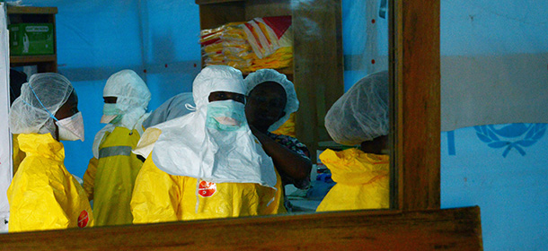 Health workers, wearing Personal Protective Equipment (PPE), are reflected in a mirror before entering a high-risk area on September 7, 2014 at Elwa hospital in Monrovia, which is run by the non-governmental French organization Medecins Sans Frontieres (Doctors without Borders -- MSF). US President Barack Obama said in an interview aired on September 7 the US military would help in the fight against fast-spreading Ebola in Africa, but warned it would be months before the epidemic slowed. The tropical virus, transmitted through contact with infected bodily fluids, has killed 2,100 people in four countries since the start of the year -- more than half of them in Liberia. AFP PHOTO / DOMINIQUE FAGET (Photo credit should read DOMINIQUE FAGET/AFP/Getty Images)