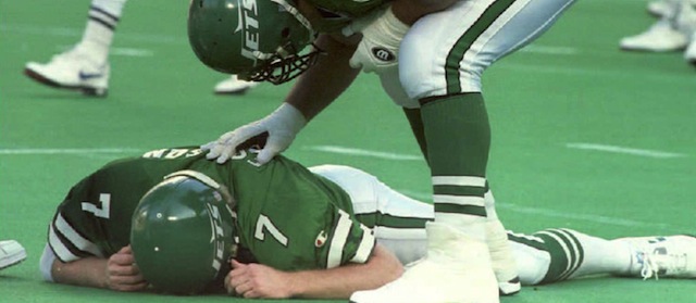 EAST RUTHERFORD, UNITED STATES: New York Jets' Matt Willig (R) and Dwayne White (L) check on their quarterback Boomer Esiason who was knocked down, and suffered a concussion, after throwing an incomplete pass in the second quarter at Giants Stadium 18 December 1994. Esiason had to leave the game and was replaced by Jack Trudeau. (Photo credit should read HENNY RAY ABRAMS/AFP/Getty Images)