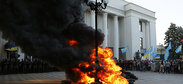 Ukrainian protesters burn tires outside the Ukrainian parliament in Kiev, Ukraine Tuesday, Sept. 16, 2014. Protesters gathered outside the building to demand parliament pass a key reform bill. (AP Photo/Sergei Chuzavkov)
