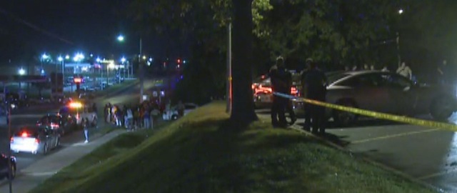 In this framegrab image courtesy of KSDK-TV police watch, right, as a crowd gathers near the scene where a police officer was shot in the arm Saturday night Sept. 27, 2014 in Ferguson, Missouri. The officer was shot in the arm and is expected to survive, St. Louis County Police Chief Jon Belmar said. (AP Photo/KSDK-TV)