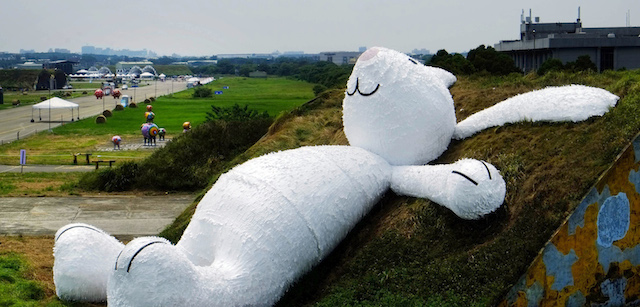 Dutch artist Florentijn Hofman's latest creation, a 25 meter (82 feet) white rabbit, leans up against an old aircraft hangar as part of the Taoyuan Land Art Festival in Taoyuan, Taiwan, Tuesday, Sept. 2, 2014. Hoffan's big yellow duck drew millions of visitors as it toured the island last year and festival organizers are hoping the rabbit will do the same. The Taoyuan Land Art Festival will take place from Sept. 9-14. (AP Photo/Wally Santana)