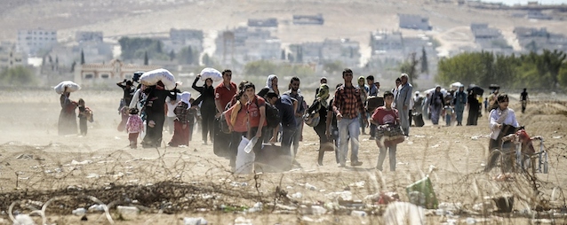 Syrian Kurdish families carry their belongings after they crossed the border between Syria and Turkey near the southeastern town of Suruc in Sanliurfa province, on September 20, 2014. Several thousand Syrian Kurds began crossing into Turkey on September 19 fleeing Islamic State fighters who advanced into their villages, prompting warnings of massacres from Kurdish leaders. Turkey on September 19 reopened its border with Syria to Kurds fleeing Islamic State (IS) militants, saying a "worst-case scenario" could drive as many as 100,000 more refugees into the country. AFP PHOTO/BULENT KILIC (Photo credit should read BULENT KILIC/AFP/Getty Images)