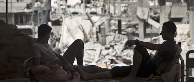 Palestinians sit inside their destroyed house after returning home in the Tufah neighbourhood in eastern Gaza City on August 31, 2014. Calm returned to the coastal enclave in a August 26 ceasefire, and Gazans were gradually starting to rebuild their lives after a bloody and destructive 50-day war, the deadliest for years. AFP PHOTO/MAHMUD HAMS (Photo credit should read MAHMUD HAMS/AFP/Getty Images)