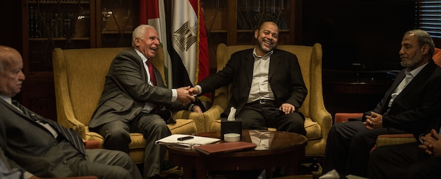 Chief Palestinian negotiator Azzam al-Ahmad (C-L) of the mainstream Fatah movement shakes hands with Hamas deputy leader Musa Abu Marzouk (C-R) in the presence of other members of the delegation at a hotel in Cairo following reconciliation talks on September 24, 2014 in the Egyptian capital. Israeli and Palestinian negotiators had agreed in Cairo the previous day to schedule new talks on a durable Gaza ceasefire for the last week of October, a Hamas official said. AFP PHOTO / KHALED DESOUKI (Photo credit should read KHALED DESOUKI/AFP/Getty Images)
