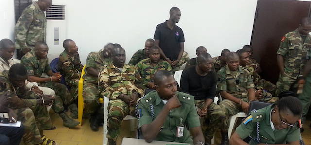 In this photo taken with a mobile phone Tuesday, Sept. 16. 2014 in Abuja Nigeria. Unidentified military prosecutors sit in the front row, while soldiers accused of an attack on their commander appear before a court martial in Abuja. Twelve soldiers fighting an Islamic insurgency in northeast Nigeria have been sentenced to death by firing squad for mutiny and attempted murder of their commanding officer. In a decision read early Tuesday by Brig. Gen. Chukwuemeka Okonkwo, the military tribunal found 12 soldiers guilty and five others innocent. One was sentenced to 28 days in jail with hard labor. ( AP Photo)