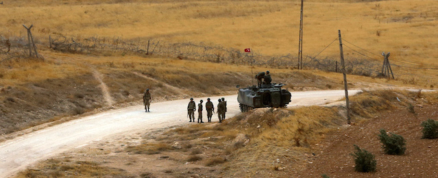 In this photo taken on Wednesday, Sept. 24, 2014, Turkish soldiers patrol a road that marks the border with Syria near Suruc, Turkey, Wednesday, Sept. 24, 2014. More than 200,000 people fleeing the Islamic State militants’ advance on Kobani, Syria, arrived in Turkey during last five days to find safety. (AP Photo/Burhan Ozbilici)