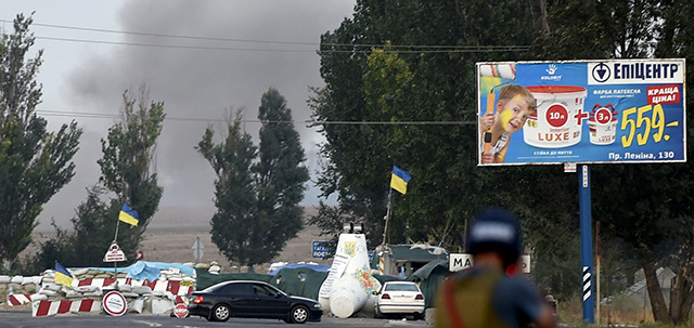 The Ukrainian flag flutters over an army checpoint as pro-Russian separatists fire heavy artillery, on the outskirts of the key southeastern port city of Mariupol, on September 4, 2014. Ukraine was poised to strike a Kremlin-backed ceasefire deal with rebel leaders after five months of a conflict that has inflamed East-West tensions. But in a sign of the future hurdles an agreement would face, AFP correspondents reported explosions on the outskirts of Mariupol as Ukrainian forces battled separatist gunmen. AFP PHOTO/PHILIPPE DESMAZES (Photo credit should read PHILIPPE DESMAZES/AFP/Getty Images)