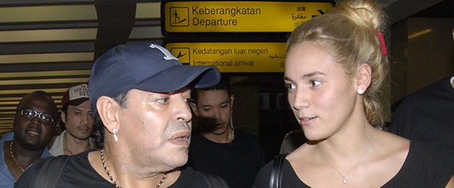 Argentina's football legend Diego Maradona (L) and his girlfriend Rocio Olivia (R) arrive at the airport in Jakarta on June 29, 2013. Maradona will attend several football events during his one-day visit. AFP PHOTO / Bima SAKTI (Photo credit should read BIMA SAKTI/AFP/Getty Images)