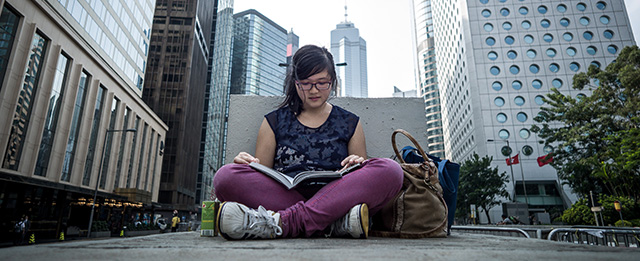 A student studies on a concrete wall separating two lanes of a road blocked by barricades set up by pro-democracy demonstrator in Hong Kong on October 7, 2014. Small knots of pro-democracy demonstrators remained on Hong Kong's streets after protest leaders agreed to talks with the government and dwindling demonstrator numbers dropped further. AFP PHOTO / Philippe Lopez (Photo credit should read PHILIPPE LOPEZ/AFP/Getty Images)
