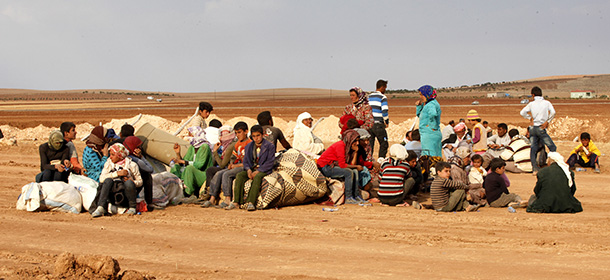 SANLIURFA, TURKEY - OCTOBER 7: Newly arrived Syrian Kurdish refugees wait with their belongings after crossing into Turkey from the Syrian border town Kobani on October 7, 2014 near the southeastern town of Suruc in Sanliurfa province, Turkey. Islamic State fighters have advanced into the Syrian Kurdish town of Kobani overnight, a monitoring group said on Tuesday. Militants are reportedly using several buildings to attack from two sides of the city. (Photo by Stringer/Getty Images)