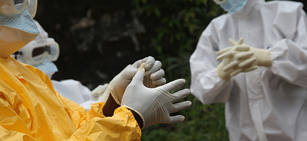 MONROVIA, LIBERIA - OCTOBER 13: Health workers dress in protective clothing before taking the body of an Ebola victim from the Island Clinic Ebola treatment center on October 13, 2014 in Monrovia, Liberia. A planned strike at Ebola treatment centers was averted as most nurses and health care workers reported for work, many saying they could not in good conscience leave their patients unattended. Health workers have been asking for increased hazard pay. They are one of the most high-risk groups of Ebola infection, as nearly 100 of them have died in Liberia alone. (Photo by John Moore/Getty Images)