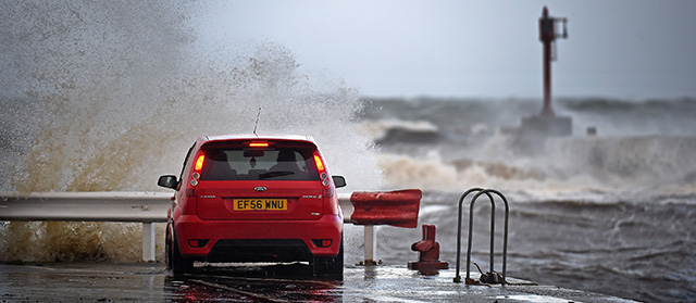 GIRVAN, SCOTLAND - OCTOBER 21: People watch from their cars as waves come over the wall at Girvan harbour on October 21, 2014 in Girvan, Scotland.Weather warnings have been issued by the Met Office for high winds and rain across parts of the country as the remnants of Hurricane Gonzalo reach Britain's coast. (Photo by Jeff J Mitchell/Getty Images)