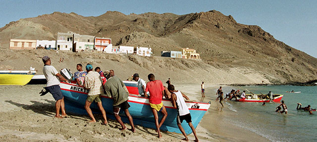 Fishermen drag a small boat up the shore in the Sao Pedro bay in the Cape Verde island of Sao Vicente Sept. 8, 2000. Visitors to the islands of Cape Verde explore a broad range of possibilities: lush mountains for hiking or cross-country cycling, arid moonscapes, pristine beaches, water sports such as wind surfing and scuba diving, and genuine African culture. (AP Photo/Armando Franca)
