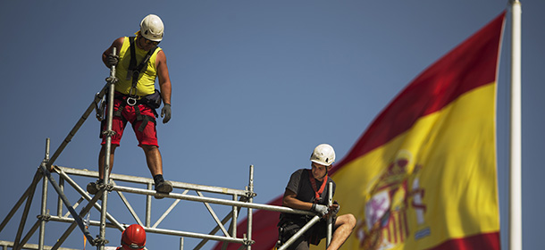 Workers build a structure in front of the Spanish flag in Madrid, Spain, Tuesday, Sept. 2, 2014. The number of people registered as unemployed in Spain grew by 8.070 in August, leaving the total number at 4.427.930 of people, Spain’s Labor Ministry said. (AP Photo/Andres Kudacki)