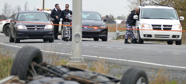 In a Monday Oct. 20, 2014 photo, investigators work at the scene near an overturned car in in St-Jean-sur-Richelieu after two soldiers were hit by a car. One of the soldiers died of his injuries early Tuesday, according to Quebec provincial police. Martin Couture Rouleau, 25, was shot and killed by police after he struck two members of the Canadian military with his car. An official familiar with the case said Rouleau had become influenced by radical Islam. (AP Photo/The Canadian Press, Pascal Marchand)