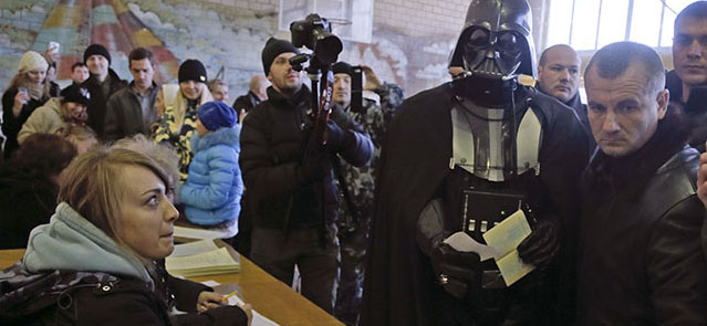 Darth Vader, previously known as Viktor Shevchenko, center, the leader of the Ukrainian Internet Party, waits to receive his ballot papers at a polling station during parliamentary elections in Kiev, Ukraine, Sunday, Oct. 26, 2014. Voters in Ukraine headed to the polls Sunday to elect a new parliament, overhauling a legislature tainted by its association with ousted President Viktor Yanukovych. Pollsters predict the Ukrainian Internet Party, which also includes a Stepan Chewbacca on its list, has little chance of getting into parliament in Sunday's vote. (AP Photo/Efrem Lukatsky)