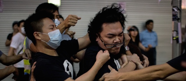 A group of men in masks rough up a man (R) who tried to stop them from removing barricades from a pro-democracy protest area in the Causeway Bay district of Hong Kong on October 3, 2014. Hong Kong has been plunged into the worst political crisis since its 1997 handover as pro-democracy activists take over the streets following China's refusal to grant citizens full universal suffrage. AFP PHOTO / ALEX OGLE (Photo credit should read Alex Ogle/AFP/Getty Images)