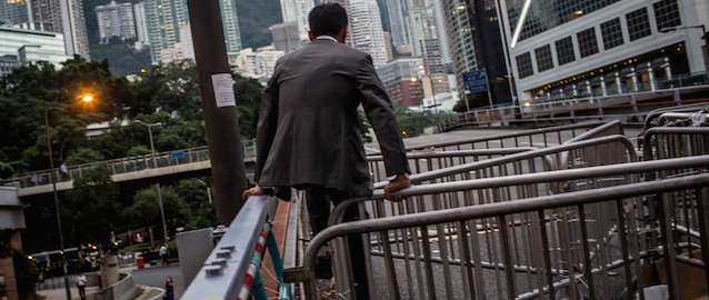HONG KONG - OCTOBER 08: A business man climbs over a road block outside Hong Kong's Government complex on October 8, 2014 in Hong Kong, Hong Kong. With many protesters returning to work and school, supporter numbers have dwindled leaving a small number defying the governments request to leave the area. Student leaders and government officials have agreed to hold talks to end the two week protests. (Photo by Chris McGrath/Getty Images)