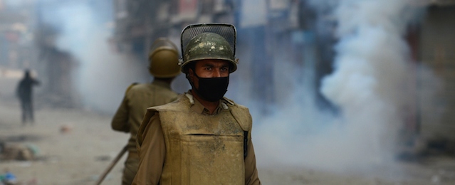 An Indian police personnel looks on during clashes with Kashmiri residents in Srinagar on October 6, 2014. Eid festivities were muted in Kashmir, devastated last month by heavy monsoon rains and floods which killed more than 450 people in the region and caused billions of dollars in damage to homes, businesses and livelihoods. Most neighbourhoods in Indian Kashmir's main city looked war-ravaged with collapsed houses and mounds of stinking garbage a month after the massive floods. Residents accuse the local government of a tardy response to the floods. Some protesters clashed with police who fired tear smoke canisters in reply. The city centre was sealed off with razor wire coils to minimize protests. AFP PHOTO/Tauseef MUSTAFA (Photo credit should read TAUSEEF MUSTAFA/AFP/Getty Images)