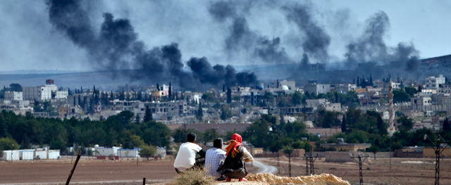 Syrian Kurdish refugees from Kobani watch fighting across the border in Kobani from a hilltop on the outskirts of Suruc, Turkey, near the Turkey-Syria border, Sunday, Oct. 26, 2014. Kobani, also known as Ayn Arab, and its surrounding areas, has been under assault by extremists of the Islamic State group since mid-September and is being defended by Kurdish fighters. (AP Photo/Vadim Ghirda)