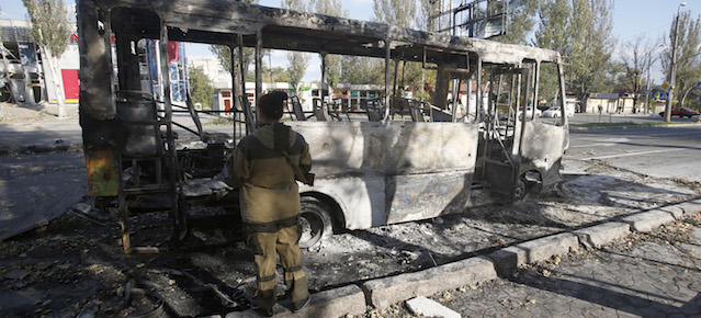 A pro-Russian rebel looks toward a destroyed bus after shelling in the town of Donetsk, eastern Ukraine, Wednesday, Oct. 1, 2014. Rebels in eastern Ukraine appear to be successfully closing in on the government-held airport of Donetsk, a strategic victory for the pro-Russian separatists that further undermines a shaky cease-fire in the region. (AP Photo/Darko Vojinovic)