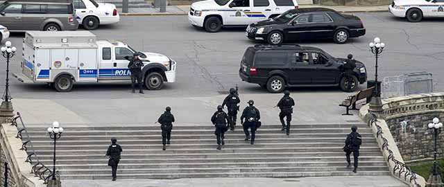 Police teams move towards Centre Block at Parliament Hill in Ottawa on Wednesday Oct. 22, 2014. A soldier standing guard at the National War Memorial was shot by an unknown gunman and people reported hearing gunfire inside the halls of Parliament. Prime Minister Stephen Harper was rushed away from Parliament Hill to an undisclosed location, according to officials. (AP Photo/The Canadian Press, Justin Tang)