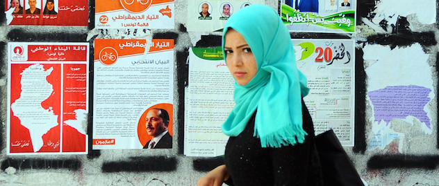 A woman walk past electoral campaign posters for the upcoming parliamentary elections in Tunis, Tunisia, Thursday, Oct. 23, 2014. Tunisians will flock to the polls on Sunday, Oct. 26, 2014, to elect representatives for a four year parliament in one of the final steps for the country's transition to democracy after overthrowing its leader more than three years ago. (AP Photo/Hassene Dridi)