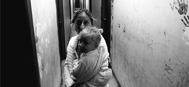 A Roma woman holds her child as she walks in the corridor of the "Best House Rom" reception centre in Rome on November 10, 2014. The "Best House Rom" reception centre is one of a dozen or so camps for Roma people in the Italian capital. A former warehouse with no windows, cooking facilities or common spaces, it currently houses over 300 people, with families of up to eight living together in single rooms. The European Commission recently questioned Italy's policy on housing Roma people, amid accusations from rights organisations of ethnic discrimination. AFP PHOTO / ALBERTO PIZZOLI (Photo credit should read ALBERTO PIZZOLI/AFP/Getty Images)