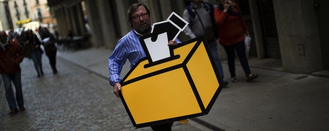 Businessman Emilio Busquets carries a drawing of a ballot box to decorate his shop ahead of voting on an informal poll, scheduled for next Sunday, in Girona, Spain, on Saturday Nov.8, 2014. The pro-independence regional government of Catalonia stages a symbolic poll on secession in a show of determination and defiance after the Constitutional Court suspended its plans to hold an official independence referendum following a legal challenge by the Spanish government. (AP Photo/Emilio Morenatti)