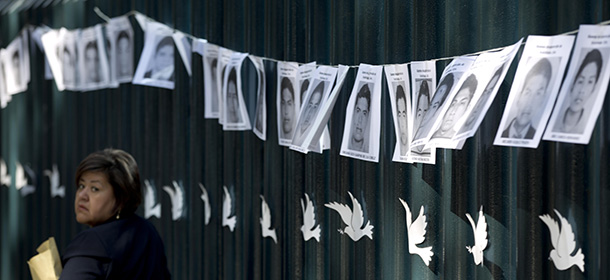 A woman walks in front of images of the 43 college rural students that remain missing, strung on the front gate of the Mexican attorney general's office in Mexico City, Wednesday, Oct. 29, 2014. Forensic experts combed a gully in southern Mexico on Tuesday for the remains of 43 missing students, as frustration mounted among relatives of both the disappeared and the detained for the lack of answers more than a month into the investigation. (AP Photo/Eduardo Verdugo)