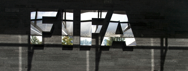 Shadows of journalists are seen next to a logo of the football's world governing body FIFA after a press conference on October 4, 2013 at ist headquarters in Zurich. FIFA said they could not get involved in labour issues in any country, amid calls for action after claims that dozens of migrant workers had died on construction projects linked to the 2022 World Cup in Qatar. FIFA President Sepp Blatter, however said that the federation could not turn a blind eye to the reports, which also alleged that thousands of other workers endured conditions akin to "modern-day slavery" in Qatar. AFP PHOTO / FABRICE COFFRINI (Photo credit should read FABRICE COFFRINI/AFP/Getty Images)