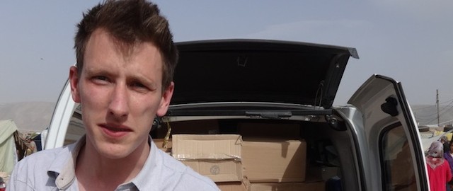 FILE - In this undated file photo provided by his family, Peter Kassig stands in front of a truck filled with supplies for Syrian refugees. The Indianapolis, Indiana, aid worker being held by the Islamic State group told family and teachers that he’d found his calling in 2012 when he decided to stay in the Middle East instead of returning to college, according to an email released Tuesday, Oct. 14, 2014 by his family. (AP Photo/Courtesy Kassig Family, File)