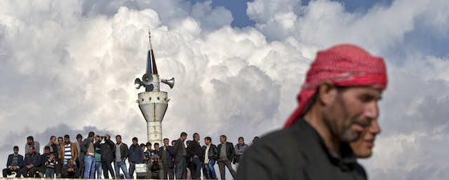 Men stand on the roof of a mosque during a solidarity rally with the Syrian city of Kobani in the village of Caykara, Turkey, on the Turkey-Syria border, just across from Kobani, Saturday, Nov. 1, 2014. Tens of thousands of Kurds are rallying in Turkish cities in solidarity with the embattled Syrian city of Kobani, which has been under a brutal siege by the Islamic State group. (AP Photo/Vadim Ghirda)