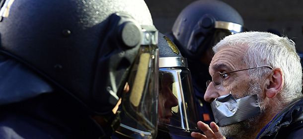 A demonstrator faces anti-riot policemen during a protest against the new public security law ("ley mordaza") approved by the lower house of parliament, in Madrid on December 20, 2014. Spain's proposed new public security law, which introduces hefty fines for unauthorised protests and allows for the summary expulsion of migrants that try to enter the country illegally, has sparked fierce opposition from human rights activists. AFP PHOTO/ PIERRE-PHILIPPE MARCOU (Photo credit should read PIERRE-PHILIPPE MARCOU/AFP/Getty Images)
