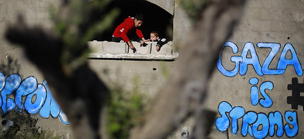 Palestinian children look out of the window of a destroyed building bearing graffiti in Gaza City's Al-Shejaiya suburb on December 25, 2014. AFP PHOTO / MOHAMMED ABED (Photo credit should read MOHAMMED ABED/AFP/Getty Images)