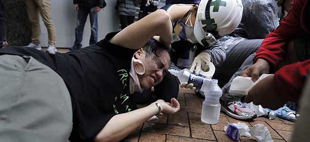 A protester is attended after being hit by pepper spray by policemen outside government headquarters in Hong Kong Monday, Dec. 1, 2014. Pro-democracy protesters clashed with police as they tried to surround Hong Kong government headquarters late Sunday, stepping up their movement for genuine democratic reforms after camping out on the city's streets for more than two months. (AP Photo/Vincent Yu)