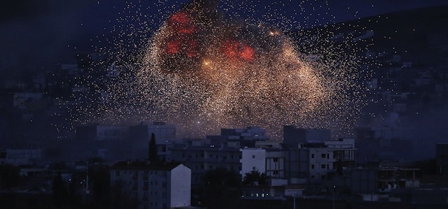 Una nuova di fiamme e fumo si alza da Kobane dopo un bombardamento della coalizione guidata dagli Stati Uniti, 20 ottobre 2014 (AP Photo/Lefteris Pitarakis, File)