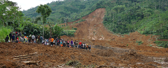 Villagers and rescuers examine the site where a landslide swept away houses in Jemblung village, Central Java, Indonesia, Saturday, Dec. 13, 2014. Torrential rains set off the mudslide down the hills into the village in central Indonesia, killing scores of people with more than 100 missing. (AP Photo/Bayu Nur)