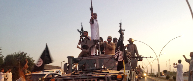 FILE - In this June 23, 2014, file photo, fighters from the Islamic State group parade in a commandeered Iraqi security forces armored vehicle down a main road at the northern city of Mosul, Iraq. The Islamic State group is employing a broad range of strategies to subdue the Sunni Muslim tribes in Syria and Iraq, wooing some with everything from cars to animal feed while brutally suppressing those that resist its rule with mass killings and home demolitions. The militants' ability to co-opt the tribes will play a significant role in deciding whether the extremists can retain control of the vast stretch of territory they controls spanning Syria and Iraq. (AP Photo/File)